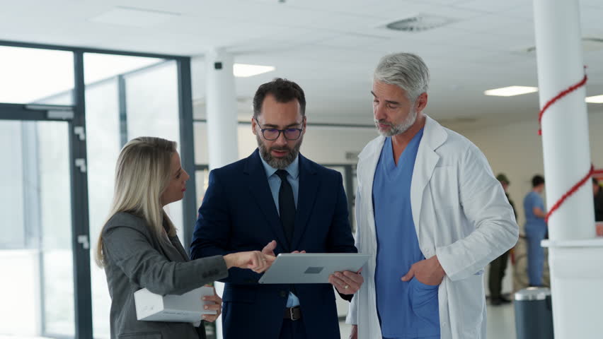 Pharmaceutical sales representatives meeting doctor in medical building. Hospital director and manager talking with head physician in modern clinic, hospital. - Powered by Shutterstock - Get 15% off with code: PIKWIZARD15
