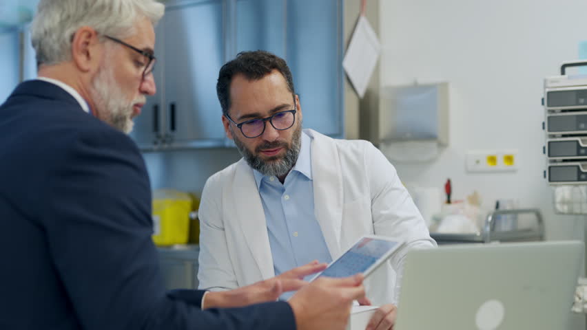 Pharmaceutical sales representative presenting new medication to doctor in medical building, holding box with medication samples. - Powered by Shutterstock - Get 15% off with code: PIKWIZARD15