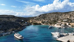 Aerial drone video of small port of Schoinousa island a safe harbour to yachts and sail boats featuring small beach of Myrsini covered in Almirikia trees, Small Cyclades, Greece