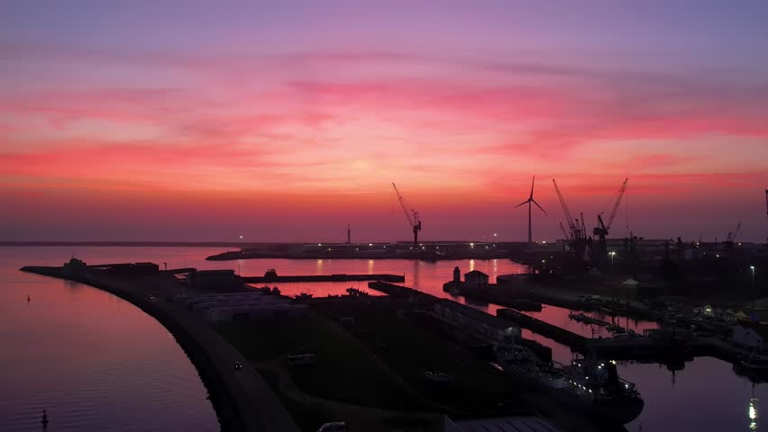 Port at sunset - drone footage of a small town harbor shot during dusk, with silhouettes of seagulls flying 