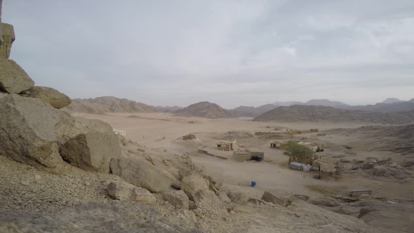 Egyptian landscape, village in the desert from a small mountain with a 4x4 vehicle coming and some kids running