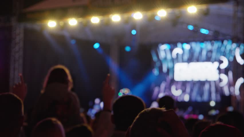 Happy people watching amazing musical concert. Bright colorful stage lighting. Selective focus, blurred. Nightlife and entertainment concept. People on music event with lights Royalty-Free Stock Footage #3436053785