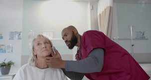 Animation of dna scanner icons over diverse male doctor checking ear of senior female patient. Check up, digital interface, connection, hospital and healthcare, digitally generated video.