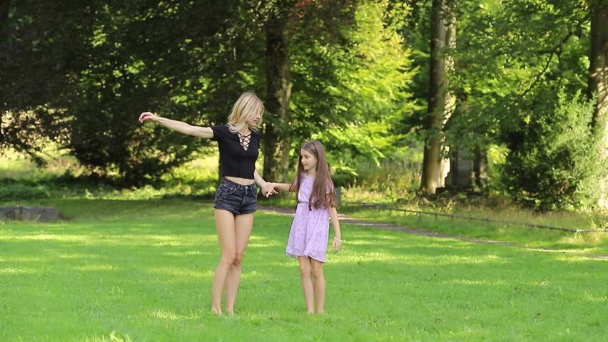 Mother and daughter jumping and holding hands in the park