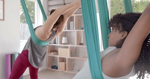 Animation of blue and white light spots over caucasian woman practicing aerial yoga. Wellbeing, energy, fitness and healthy lifestyle, digitally generated video.