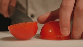 Chef cutting up a tomato with a knife. close up