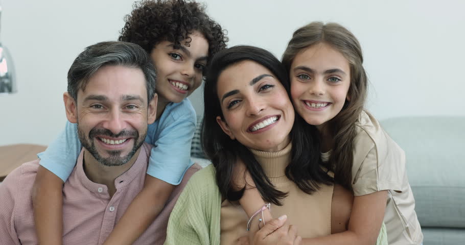 Close up portrait beautiful young multinational parents with little children laugh look at camera, feeling unconditional love, spend time together. Family ties, childcare, adoption, happy parenthood Royalty-Free Stock Footage #3436173783