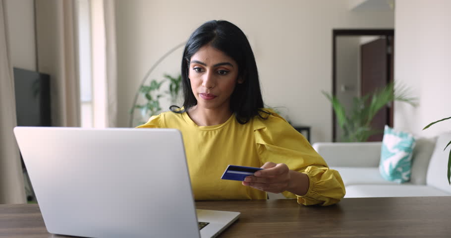 Young Indian woman sit at desk using laptop, try to make electronic payment by card, feels stressed, disappointed due to lack of money, extra fees for transaction, insecure payment, fraud and scams Royalty-Free Stock Footage #3436213861