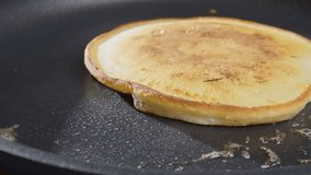 Baking pancakes at home. An American pancake is baked in a black pan. 4k Slow motion video, 100fps. 