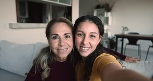 Attractive mature mother and grown-up daughter making selfie, fooling in front of smartphone camera, hold device staring at cam, having fun together on weekend. Blogging, family pastime, video call