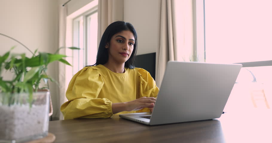 Young Indian business woman browse wireless internet using laptop, enjoy communication with friends on social networks, type message, web surfing information, doing telework, freelance job from home Royalty-Free Stock Footage #3436244643