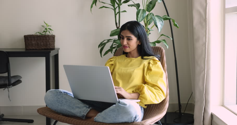 Attractive Indian woman make on-line purchase, look through fashion websites buy via marketplace sitting in comfortable armchair with laptop. Freelance job, internet usage for chat, business or study Royalty-Free Stock Footage #3436249813