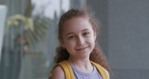 Portrait beautiful of a happy school girl, a smiling school girl, a little girl with a backpack, standing alone on a sunny street outdoors, a pretty face primary five grade student 4 K.