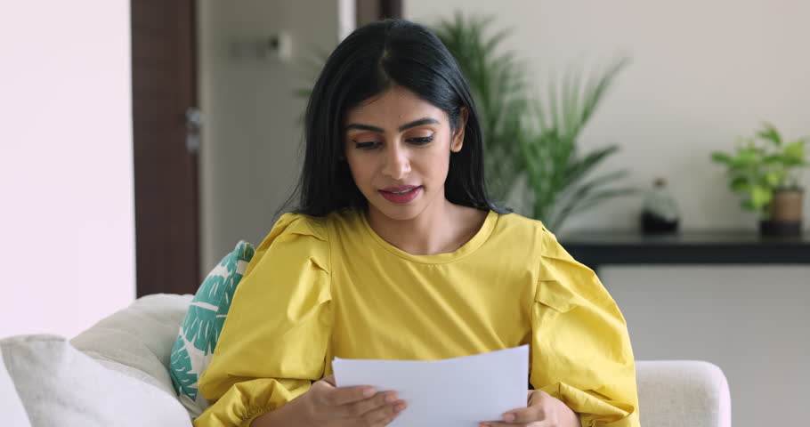 Frustrated young Indian woman sit on sofa, hold document, read bad negative news in paper letter, feel distressed, received notice of bankruptcy, concerned about bank debt. Financial problem, eviction Royalty-Free Stock Footage #3436266381