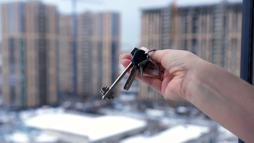 Close-up of a woman's hand holding a bunch of keys to a new apartment against the background of multi-storey buildings Royalty-Free Stock Footage #3436317691