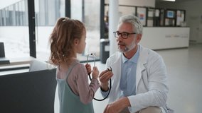 Doctor examining little girl's ear using otoscope, looking for infection. Friendly relationship between the doctor and the child patient. - Powered by Shutterstock - Get 15% off with code: PIKWIZARD15