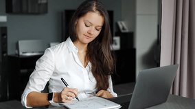 Young woman using laptop in home workplace, writing notes, e-learning education concept. High quality 4k footage
