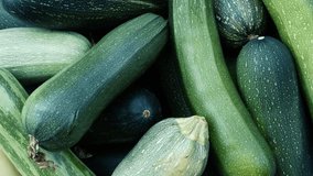 Full HD video with rotation and zoom. Top view. Box of fresh raw juicy green zucchini. Concept of harvest, buying farm food at street market in Tbilisi. Showcase of fruit shop. Grocery store counter