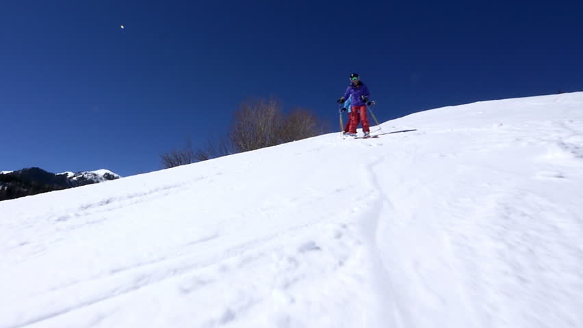 Cameraman skis alongside with two female expert skiers on a sunny day at the Canyons Village Park City, Utah. 
