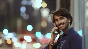 View of young man using a smartphone at night time with city view landscape in the background. High quality video