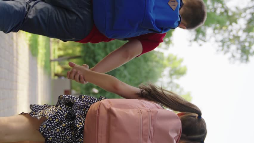 boy girl holding hands running through park school, child with school backpacks running along sidewalk school lesson, cheerful classmates running hand hand with bags, teamwork group children, boy girl