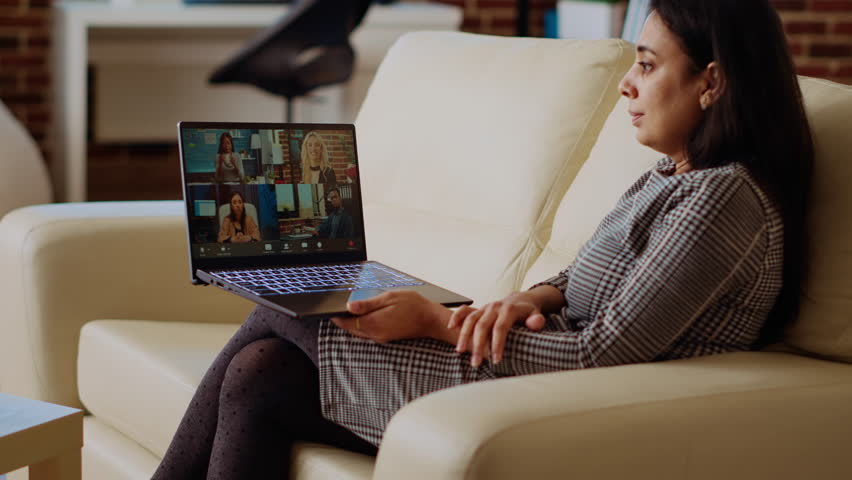 Indian remote professional holding q and a session with multiethnic webinar participants via teleconference meeting. Internet videocall host on couch at home engaging in discussions with trainees Royalty-Free Stock Footage #3436640149