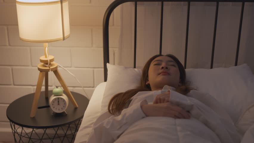 Asian beautiful insomnia ​woman lying down on bed in bedroom at night. Attractive beautiful depressed young woman feeling upset, worried and concerned cannot sleep from insomnia in bedroom in house. Royalty-Free Stock Footage #3436696175