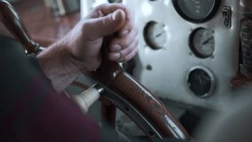 The ship's captain turns the wheel of the ship. Clip. Close up of man hand turning wooden steering wheel.