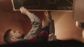 Vertical medium shot of two diverse male programmers drawing scheme of computer program on chalkboard while working together in old-fashioned room - Powered by Shutterstock - Get 15% off with code: PIKWIZARD15