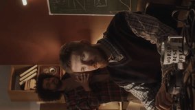 Vertical medium lowkey shot of young bearded Caucasian programmer working on software startup and showing progress on computer to his team, working and living together in 90s style garage - Powered by Shutterstock - Get 15% off with code: PIKWIZARD15