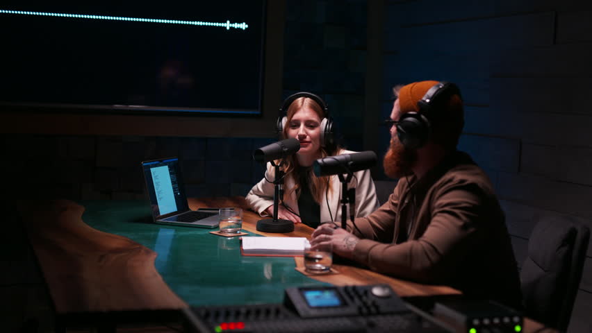 Positive couple radio hosts wearing headphones talking at studio Royalty-Free Stock Footage #3436833235
