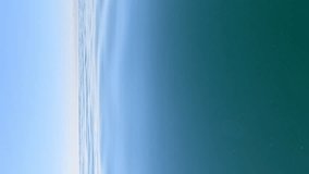 Vertical aerial view on sea water surface, camera flies over clear sea water. Sun glare. Abstract nautical summer ocean nature. Holiday, vacation and travel concept. Nobody. Weather and climate change