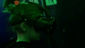 VR salon. Girl is actively playing in a virtual reality game. Virtual reality helmet and a pair of controllers in her hands. Gaming industry expansion. Dark room - Powered by Shutterstock - Get 15% off with code: PIKWIZARD15