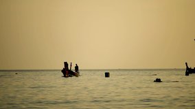 Travel video silhouette Long-tail boats sailing on the andaman sea with golden light of the Sun before sunset in travel or transportation concept.