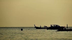 Travel video silhouette Long-tail boats sailing on the andaman sea with golden light of the Sun before sunset in travel or transportation concept.