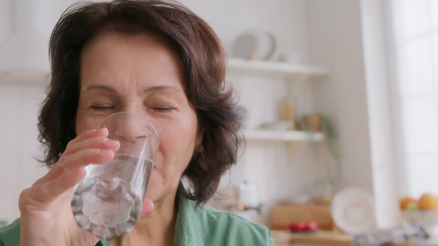 close up view of elderly woman holding pill on hand, takes medicine and drink water. feels good and positive, smiling. old people medicare