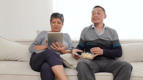 senior couple eating popcorn and watching television on sofa - Powered by Shutterstock - Get 15% off with code: PIKWIZARD15