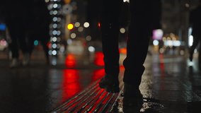 Rear back view male feet steps crossing city street at night. Man wearing dark leather boots goes on sidewalk in city. Low angle legs walking sidewalk, rainy autumn weather, reflected car lights - Powered by Shutterstock - Get 15% off with code: PIKWIZARD15