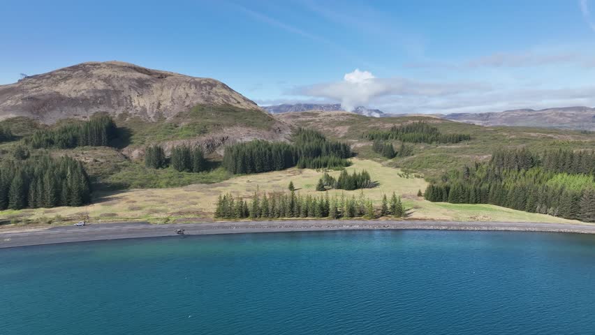 A pebble beach on Thingvallavatn lake in Iceland with the Nesjavallavirkjun geothermal powerplant in the background