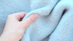 Close-up woman hand stroking over the surface knitted soft wool alpaca cloth or warm fluffy sweater. Handcraft blue knitting woolen fabric.  - Powered by Shutterstock - Get 15% off with code: PIKWIZARD15