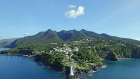 Drone flying towards lighthouse at Vieux-Fort with beautiful landscape in background, Guadeloupe. Aerial approach and sky for copy space