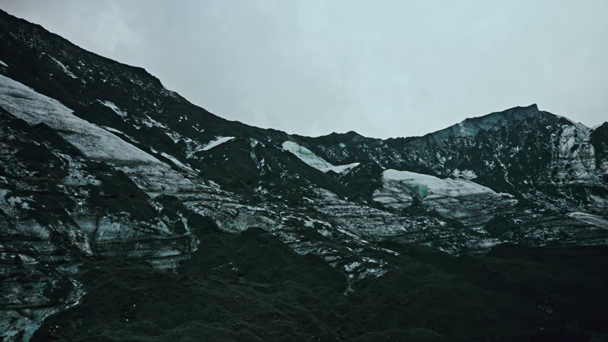 Panoramic view of the majestic Myrdalsjokull glacier in souther Iceland. Black volcanic terrain surrounded by icy landscape. Royalty-Free Stock Footage #3437030765