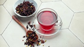Glass cup of hot hibiscus tea and dried Hibiscus tea leaves. 
