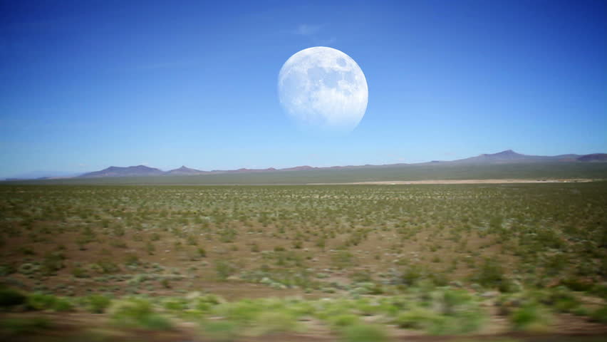 Driving through the desert with the full moon in the distance.