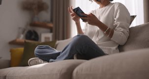 On calm weekend day, girl sits on sofa, sunlight fills room, she enjoys company of her online friends. Its peaceful and relaxing morning filled with heartfelt communication and laughter. Cinematic AD.