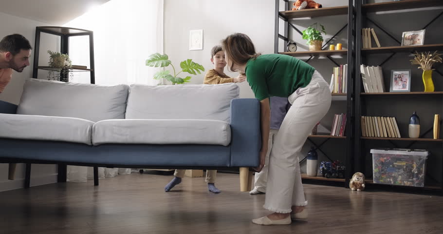 Family moving new couch into the living room. Little kids help their parents moving furniture, full family fall on new couch hug and smile. Relocation, mortgage concept Royalty-Free Stock Footage #3437193509