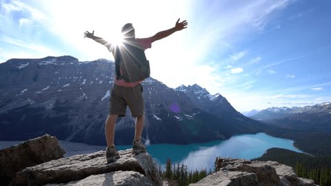 Hiker reaches mountain top above lake, arms outstretched.
Young man hiker reaches the top of the mountain and outstretches his arm.
Achievement in nature 