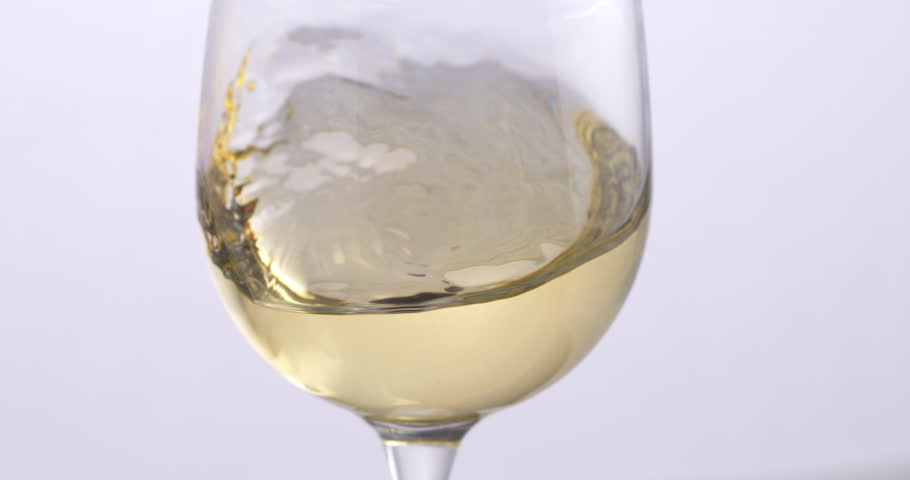 Super slow motion close up of white wine is being swirled in transparent glass by winemaker or sommelier for flavor tasting and quality checking isolated on light background at 1000 fps. Royalty-Free Stock Footage #3437222821