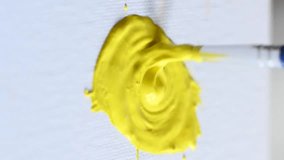 Close-up artist painting with yellow gouache on a white sheet. Vertical video. 
