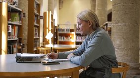 Female adult student learning new educational subject in library Middle aged woman using laptop in studying and research for Scientific materials online in Internet. Upgrade professional qualification - Powered by Shutterstock - Get 15% off with code: PIKWIZARD15